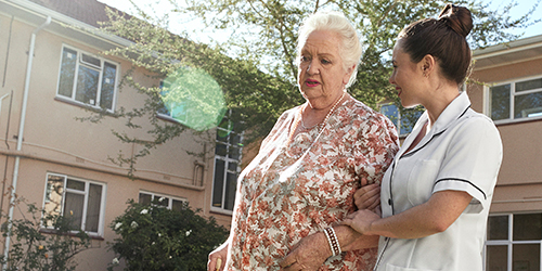 En sjuksköterska och en äldre kvinna på en promenad utomhus